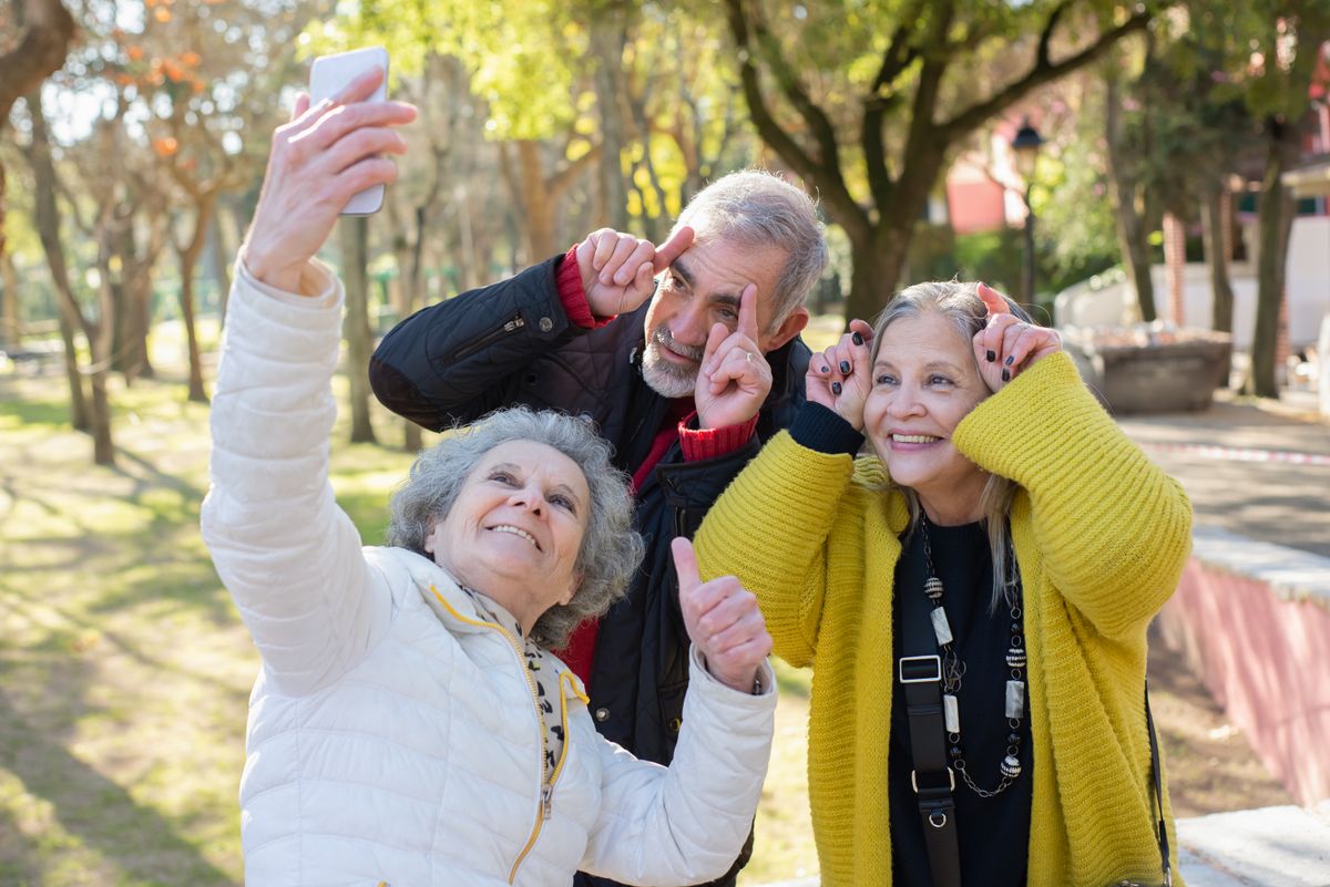 Trois seniors complices et souriants dans un parc